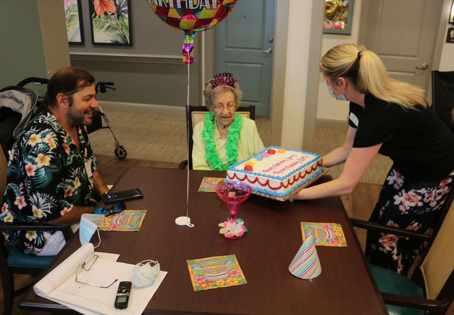 Amanda Jones, memory care director for Starling at Nocatee Assisted Living & Memory Care, right, holds out a birthday cake to 102-year-old Dorothy Coy. At left is grandson Matt Coy.
